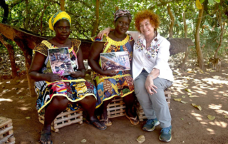 la familia Bijagó de Guinea-Bissau reunits a l'exterior d'una cabana tradicional, envoltats de natura tropical i elements culturals típics